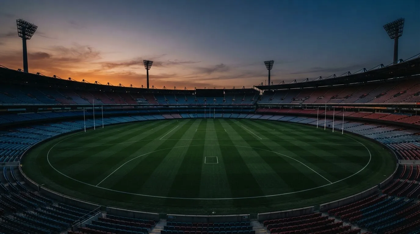 An empty football stadium with floodlight masts at dusk