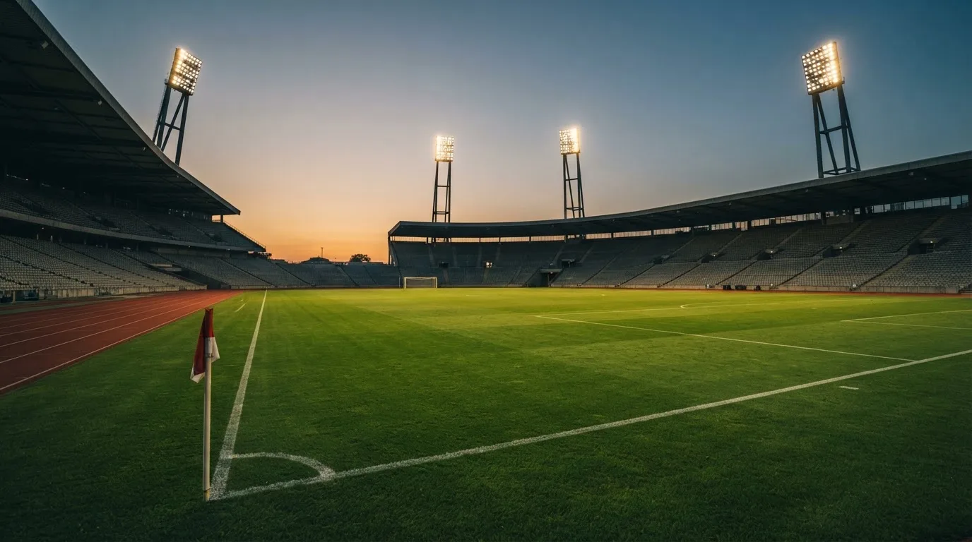 An empty football stadium with floodlight masts at dusk