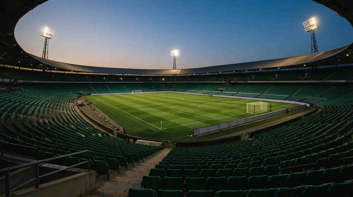 An empty football stadium with floodlight masts at dusk