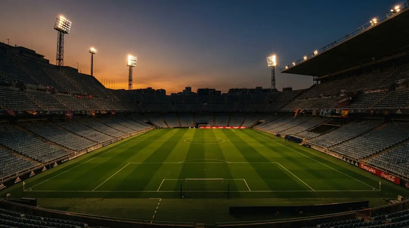 An empty football stadium with floodlight masts at dusk