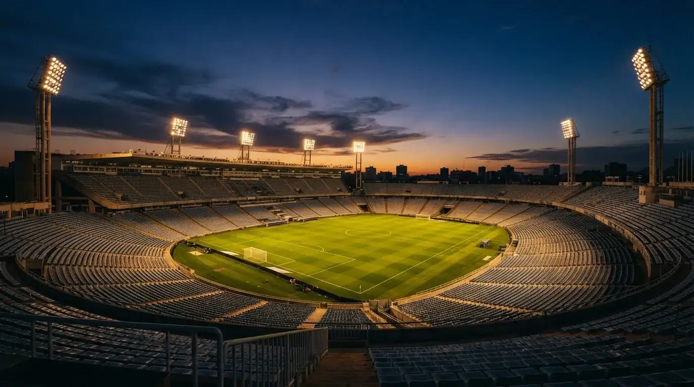 An empty football stadium with floodlight masts at dusk