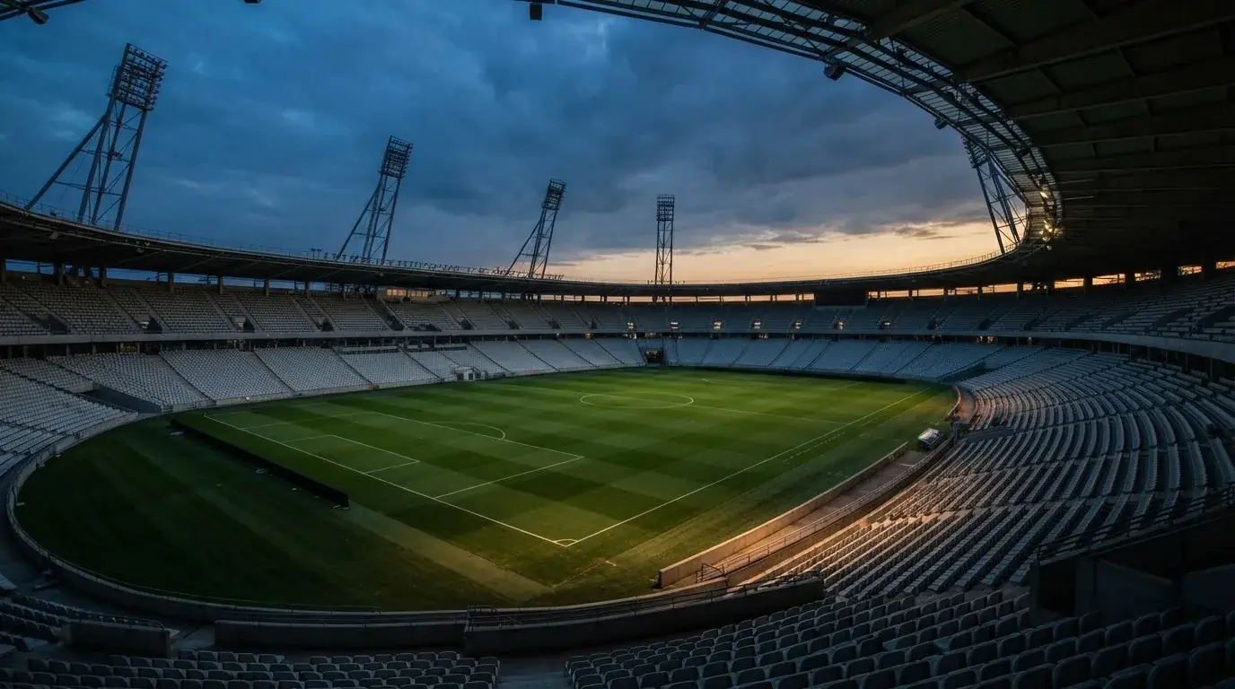 An empty football stadium with floodlight masts at dusk