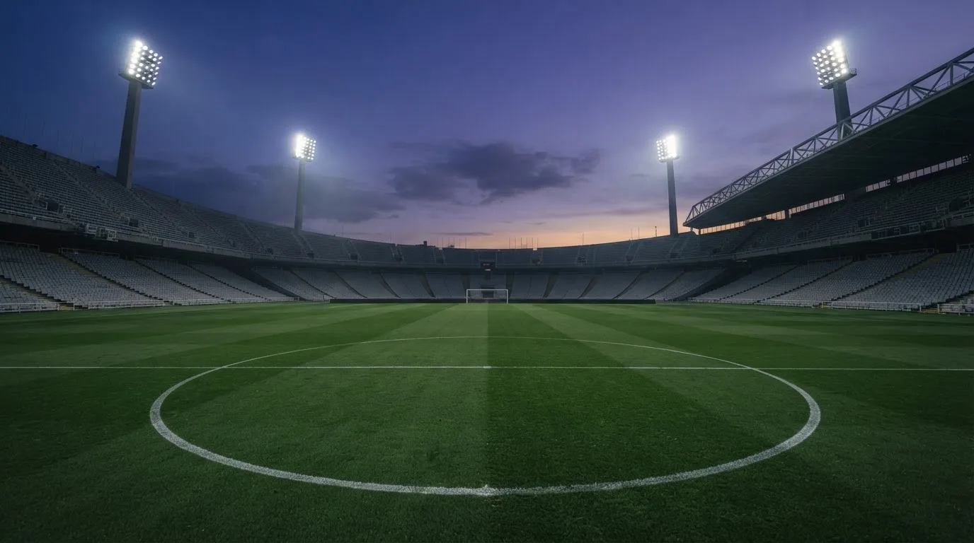 An empty football stadium with floodlight masts at dusk