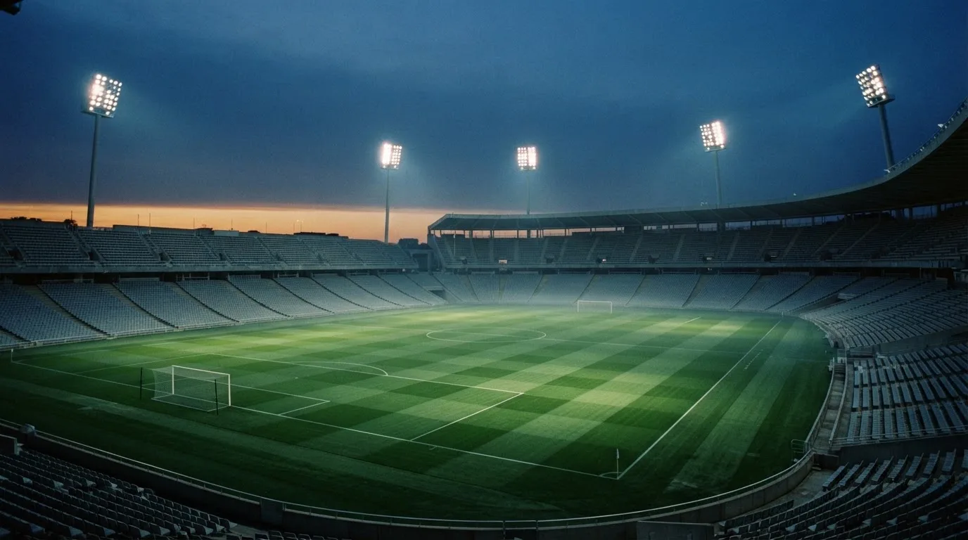 An empty football stadium with floodlight masts at dusk