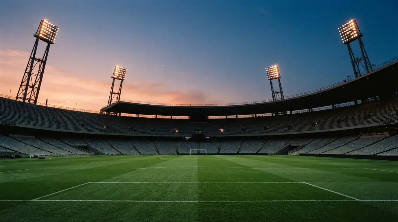 An empty football stadium with floodlight masts at dusk