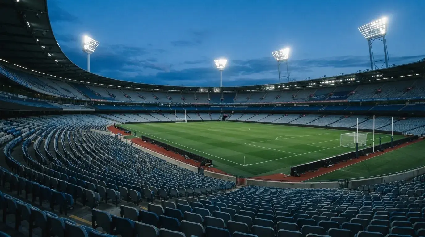 An empty football stadium with floodlight masts at dusk