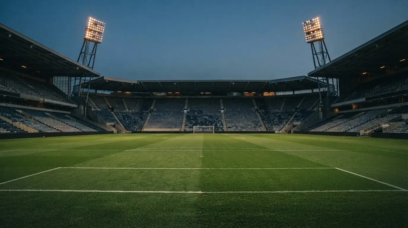 An empty football stadium with floodlight masts at dusk