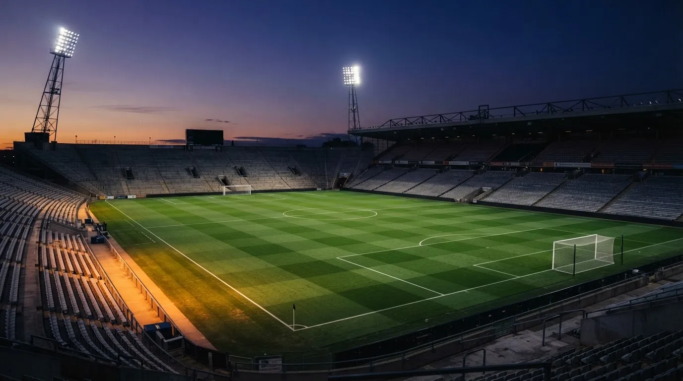 An empty football stadium with floodlight masts at dusk