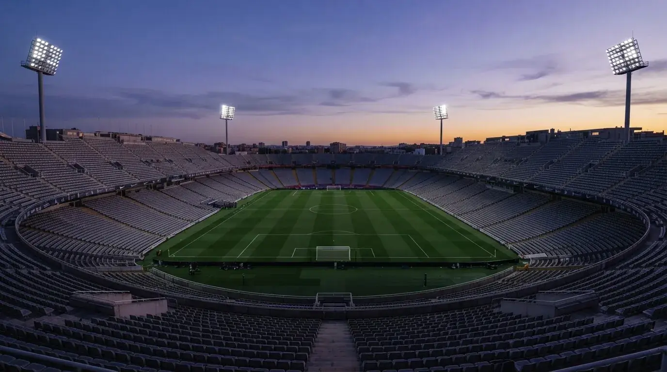 An empty football stadium with floodlight masts at dusk