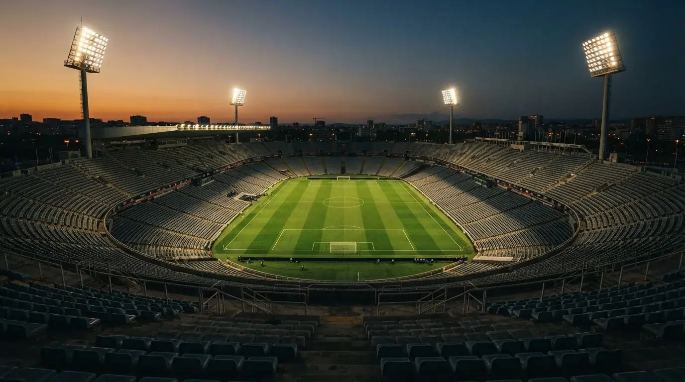 An empty football stadium with floodlight masts at dusk