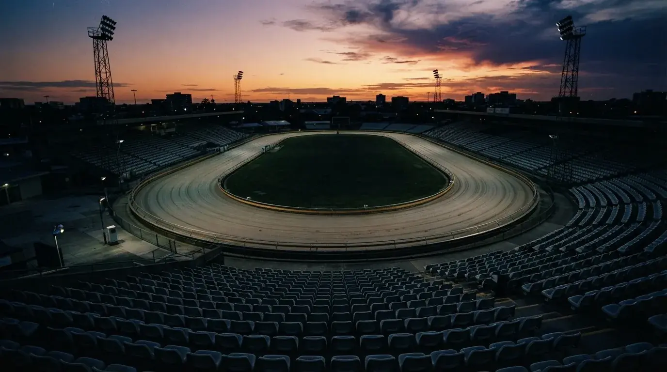 An empty football stadium with floodlight masts at dusk
