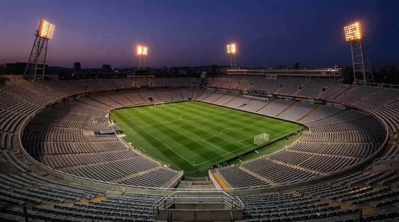 An empty football stadium with floodlight masts at dusk