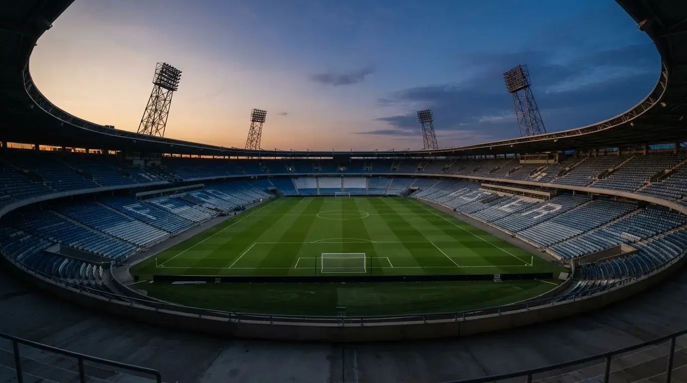 An empty football stadium with floodlight masts at dusk