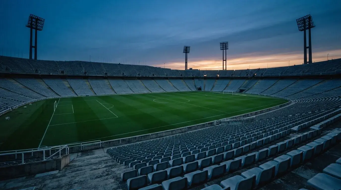 An empty football stadium with floodlight masts at dusk