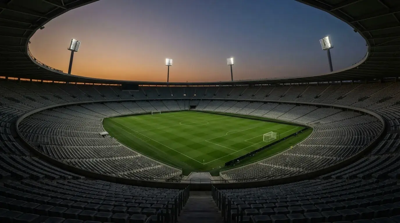 An empty football stadium with floodlight masts at dusk