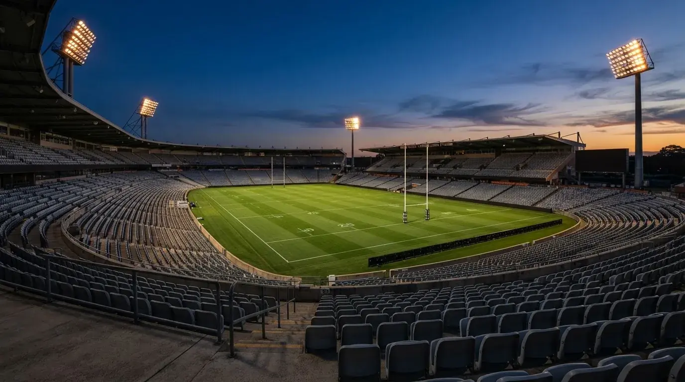An empty football stadium with floodlight masts at dusk